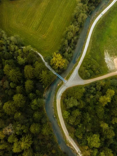 Zeller’s Quartier – das HerZ der Stadt Königsbrunn Luftaufnahme eines grünen Waldes, eines Flusses und von Wegen mit einer kleinen Brücke