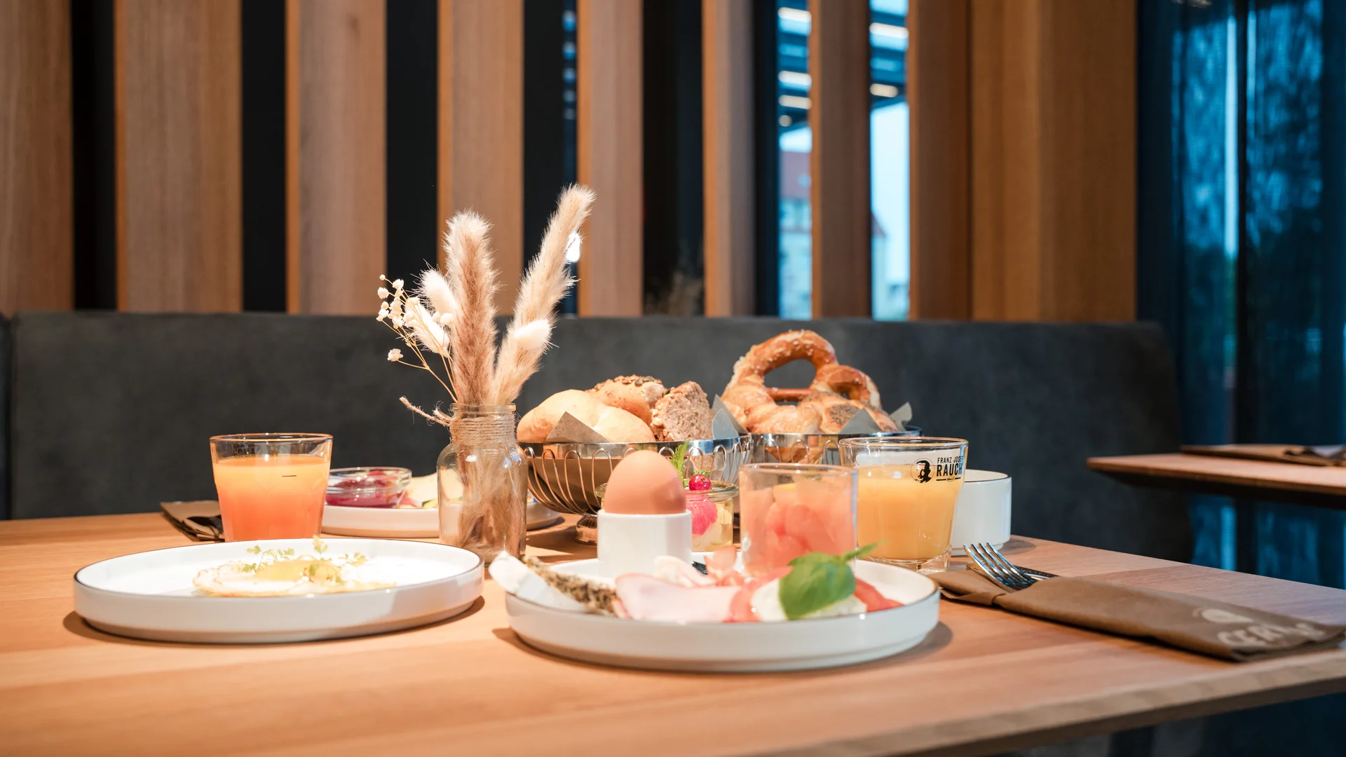 Ihr besonderes Hotel in Königsbrunn: Zeller’s Quartier Frühstückstisch mit Brötchen, Ei, Aufschnitt und Orangensaft in modernem Café