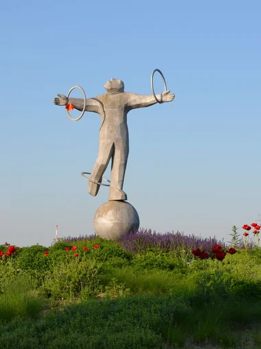 Entdecken Sie Königsbrunn! Statue einer Figur mit ausgebreiteten Armen und Reifen in der Natur