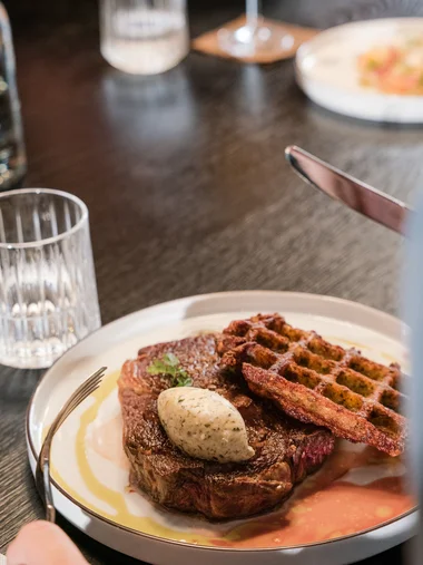 Speisekarten Steak mit Kräuterbutter und knusprigen Waffeln auf weißem Teller