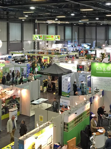 Zeller’s Quartier: Hotel Nähe Messe Augsburg und München Indoor-Messe mit verschiedenen Ständen und Menschen, die herumlaufen und sprechen