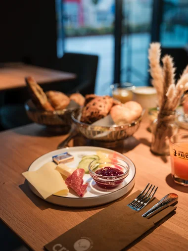 Ihr Start in den Tag: Frühstück in Königsbrunn Vorspeise mit Käse, Salami, Dressing und Brot auf Holztisch im Restaurant