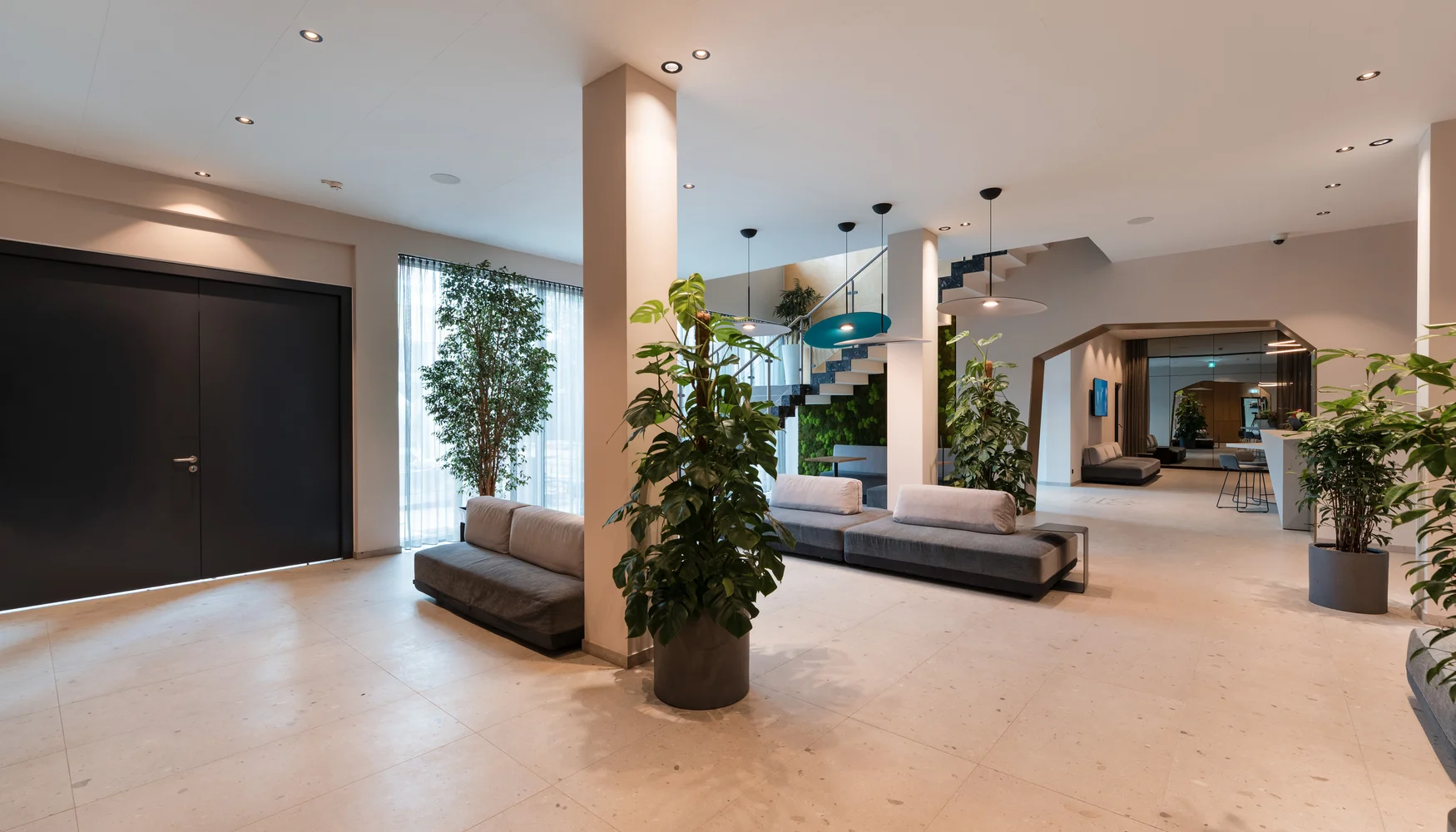 Ihre Gastgeber in Zeller’s Quartier Moderner Empfangsbereich mit Sitzbänken, Pflanzen und Treppe