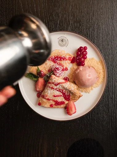 Cervus: das Restaurant in Königsbrunn mit dem gewissen Extra Hand bestreut Pfannkuchen mit Puderzucker und roten Beeren auf Teller