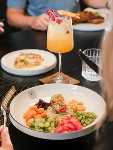 Cervus: das Restaurant in Königsbrunn mit dem gewissen Extra Bunte Gemüseplatte und Cocktail auf einem Esstisch im Restaurant