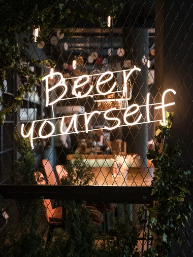 Ihr besonderes Hotel in Königsbrunn: Zeller’s Quartier Neonlicht mit dem Text Beer yourself an einem Zaun vor einem Café