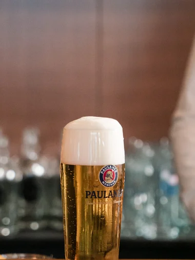 Biergarten rund um Königsbrunn gesucht? Ein Glas Paulaner Bier mit Schaum auf einem Bierdeckel auf der Bar