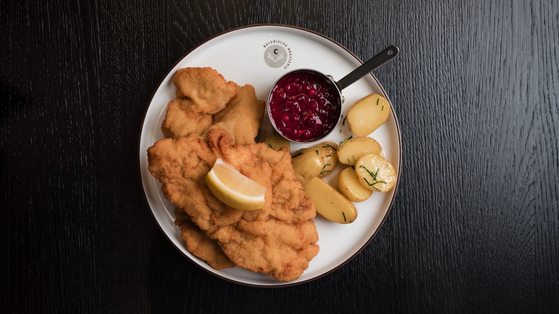 Speisekarten Teller mit Wiener Schnitzel, Bratkartoffeln, Preiselbeersauce und Zitronenscheibe