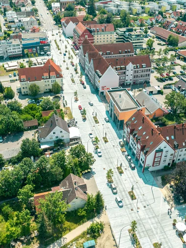 Entdecken Sie Königsbrunn! Luftaufnahme eines Wohngebiets mit Straßen, Häusern und Bäumen bei Sonnenschein