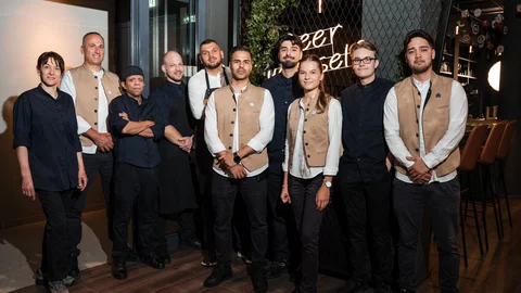 Zeller’s Quartier und Cervus in Königsbrunn: Stellenangebote Gruppenfoto von Restaurantmitarbeitern in Uniform vor Wand mit Neonlicht