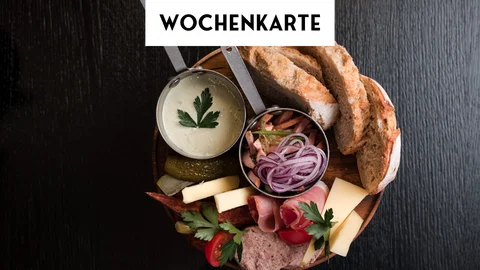 Wochenkarte Brot, Aufschnitt, Käse und Dip auf Holzbrett vor Wochentafel